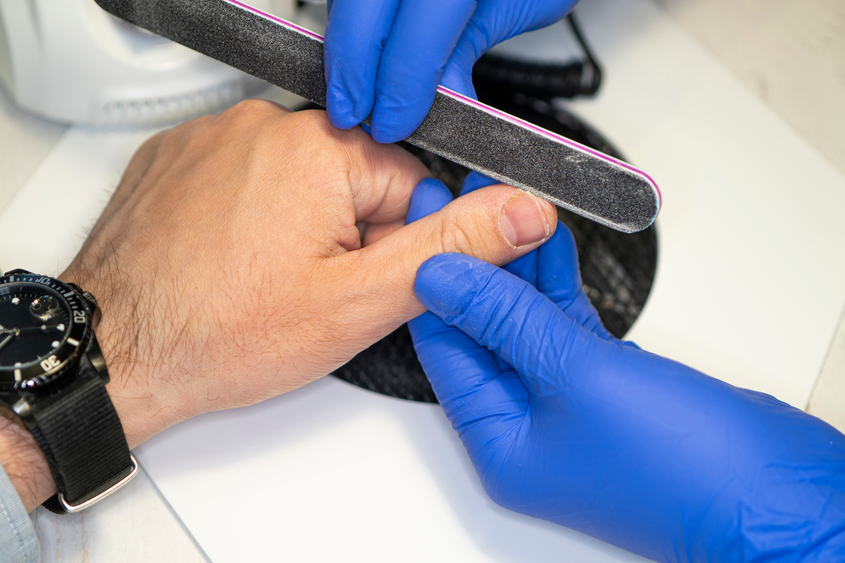 Manicurist filing man's nails in salon. Men's manicure. Hand care for men. a man's hand on the manicure procedure.